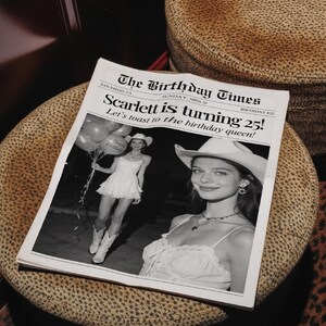 May include: A black and white newspaper titled "The Birthday Times" with the headline "Scarlett is turning 25!" and a photo of a woman in a cowboy hat. The newspaper is on a patterned surface.