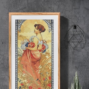 May include: A framed print of a woman in a long, flowing pink dress holding a bouquet of flowers. The woman is standing in a field of wheat and poppies. The print is in an ornate frame with a gold border.