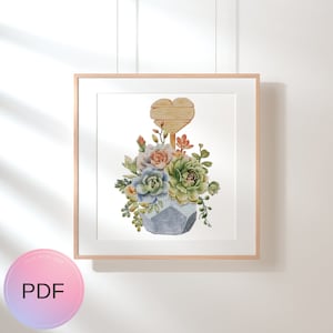 May include: A cross stitch pattern featuring a watercolor illustration of a succulent plant arrangement in a blue geometric pot with a wooden heart sign above it.