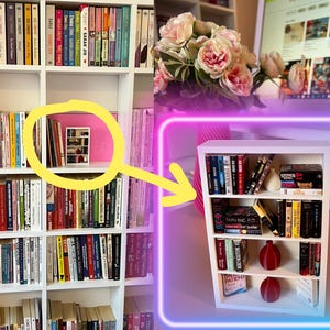 May include: A miniature white bookshelf filled with books, decorative vases, and a small ceramic object. The bookshelf is set against a backdrop of a larger bookshelf and a computer screen. The image is framed with a neon purple and blue border.