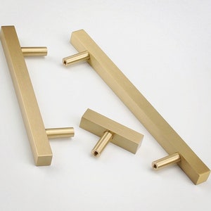 Op de afbeelding: Drie gouden kastgrepen in verschillende maten. De grepen zijn rechthoekig met afgeronde hoeken en hebben een geborstelde afwerking.
