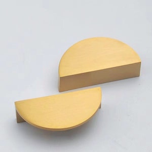 Peut inclure: Deux poignées de cabinet en demi-cercle de couleur or. Les poignées sont en métal et ont une finition brossée.