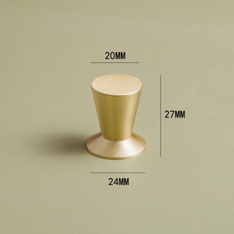 Op de afbeelding: Een gouden metalen kastknop met een afgeronde bovenkant en een uitlopende basis. De knop is 20 mm in diameter, 27 mm hoog en 24 mm breed.