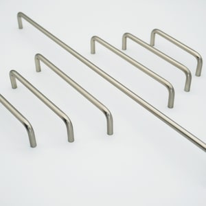 Op de afbeelding: Een set van zes geborsteld nikkel kastgrepen in verschillende maten. De grepen zijn allemaal in dezelfde stijl, met een eenvoudige, afgeronde vorm.