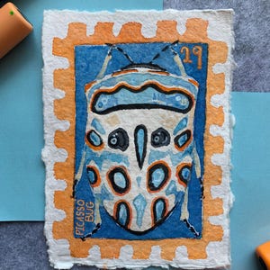 May include: A rectangular watercolour painting on textured paper depicting a Picasso bug inside a postage stamp frame. The bug is white with blue and orange markings. The frame is orange with a blue background. Text reads 29 and PICASSO BUG.