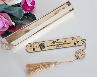 May include: Gold bookmark with a tassel and Arabic calligraphy that reads "Recite in the name of your Lord who created (Quran 96:1)".