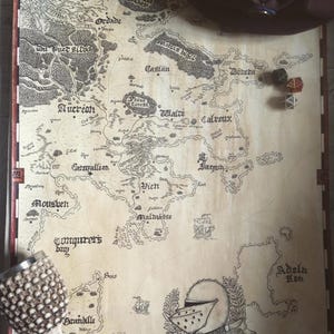 May include: A hand-drawn map of a fictional land with names like "Aucréon", "Campallion", "Calvoux", "Donera", "Grandille", "Malmásse", "Moushen", "Ordade", "St. Jaquin", "Talve", "Viett", and "Learene Legend".