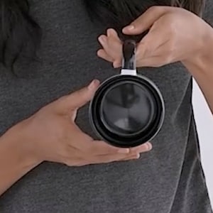 May include: A black collapsible travel mug with a white stripe around the rim. The mug is made of durable, lightweight material and is perfect for taking your favorite beverage on the go.