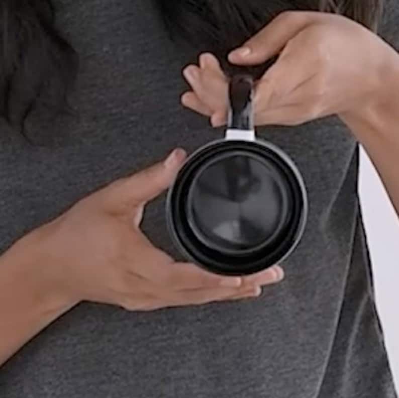 May include: A black collapsible travel mug with a white stripe around the rim. The mug is made of durable, lightweight material and is perfect for taking your favorite beverage on the go.