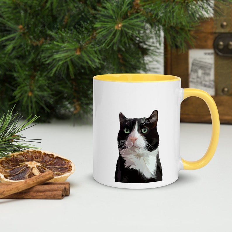 May include: A white ceramic mug with a yellow rim and handle. The mug features a black and white cat with green eyes.
