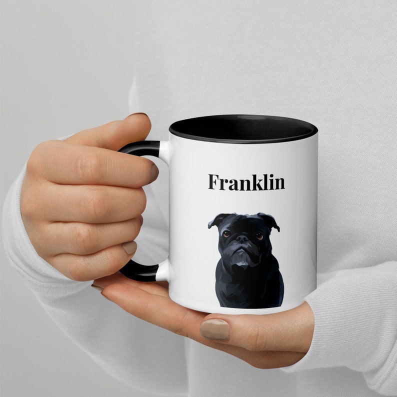 May include: White ceramic mug with a black rim and handle. The mug has a black and white illustration of a pug and the name "Franklin" printed on it.