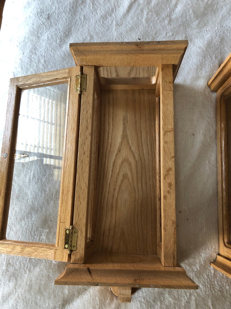K&ouml;nnte beinhalten: Ein Holzausstellungsvitrine mit einer Glast&uuml;r und Messing Scharnieren. Die Vitrine ist offen und leer.