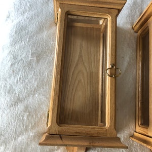 K&ouml;nnte beinhalten: Zwei Holzauslagen mit Glasfronten und Messingbeschl&auml;gen. Die Auslagen haben ein schlichtes, traditionelles Design und eignen sich ideal f&uuml;r die Pr&auml;sentation kleiner Gegenst&auml;nde.
