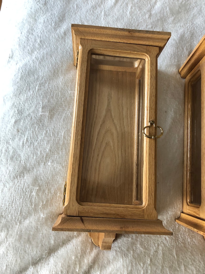 K&ouml;nnte beinhalten: Zwei Holzauslagen mit Glasfronten und Messingbeschl&auml;gen. Die Auslagen haben ein schlichtes, traditionelles Design und eignen sich ideal f&uuml;r die Pr&auml;sentation kleiner Gegenst&auml;nde.