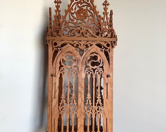 May include: A wooden wall-mounted shelf with intricate gothic-style carvings. The shelf has a pointed archway and a decorative top with a cross.