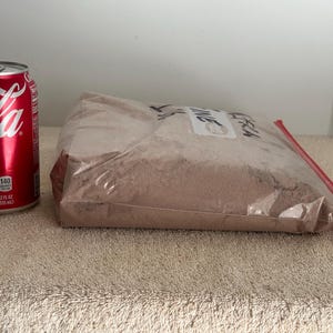 May include: A brown powder in a clear plastic bag with a red zipper. The bag is labeled "Fresh Thyme". A can of Coca-Cola is in the background for size comparison.