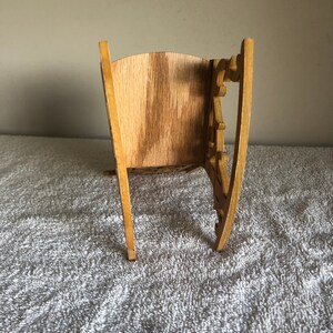 Puede incluir: Un modelo de mecedora de madera con detalles intrincados y un acabado de madera natural.