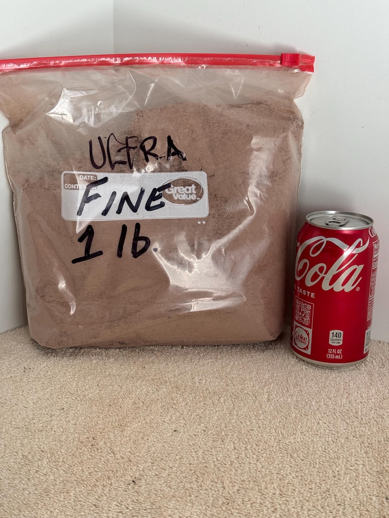 May include: A clear plastic bag filled with a brown powder labeled "ULTRA FINE 1 LB." with a "Great Value" sticker. A can of Coca-Cola is next to the bag.
