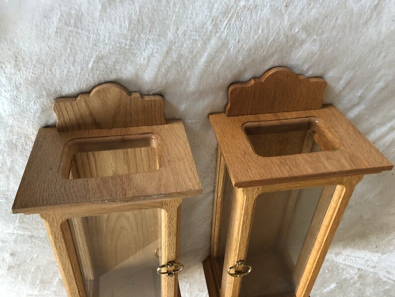 K&ouml;nnte beinhalten: Zwei Holzauslagen mit Glasfronten und verzierten Holzoberteilen. Die Auslagen sind aus hellbraunem Holz gefertigt und haben ein schlichtes Design.