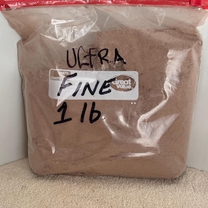 May include: A clear plastic bag filled with brown powder labeled "ULTRA FINE 1 LB" with a "Great Value" sticker.