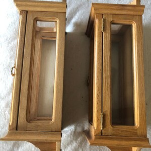 K&ouml;nnte beinhalten: Zwei Holzauslagen mit Glast&uuml;ren und einer hellen Holzoptik. Die Auslagen haben ein schlichtes Design mit einem kleinen dekorativen Rand an den Kanten.