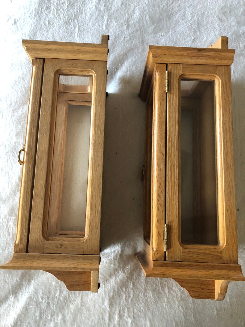 K&ouml;nnte beinhalten: Zwei Holzauslagen mit Glast&uuml;ren und einer hellen Holzoptik. Die Auslagen haben ein schlichtes Design mit einem kleinen dekorativen Rand an den Kanten.