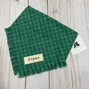Peut inclure: Bandana pour chien de couleur verte avec un bord effiloché et une étiquette blanche sur laquelle est inscrit "Piper".