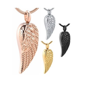 Könnte beinhalten: Ein Set aus vier Engelsflügel-Asche-Anhängern. Die Anhänger sind in Roségold, Silber, Schwarz und Gold erhältlich. Jeder Anhänger verfügt über ein detailliertes Flügeldesign.