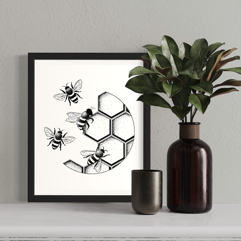 Puede incluir: Ilustraci&oacute;n en blanco y negro de abejas volando alrededor de un panal. La ilustraci&oacute;n est&aacute; enmarcada y se muestra en una pared blanca junto a un jarr&oacute;n con hojas verdes.