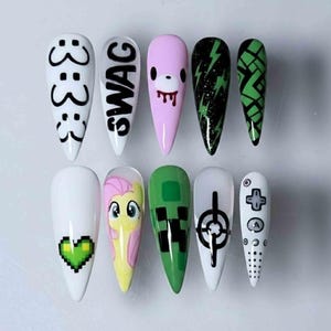 Könnte beinhalten: Ein Set aus zehn langen, spitz zulaufenden Acrylnägeln mit verschiedenen Designs. Die Designs umfassen ein pixeliges grünes Herz, das Wort "SWAG", ein Bärengesicht und einen Videospiel-Controller. Weitere Nägel zeigen Blitze und geometrische Muster.