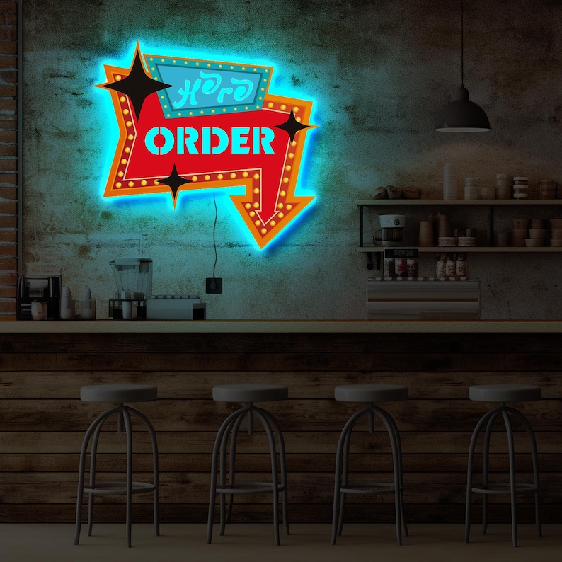May include: A neon sign with a red arrow pointing down and the words "Here to Order" in blue and orange letters. The sign is lit up with blue and orange lights and is hanging on a brick wall. There are four bar stools in front of a wooden counter.