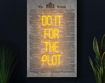 Puede incluir: Impresión enmarcada de una página de periódico vintage con las palabras "DO IT FOR THE PLOT" en luces de neón amarillas brillantes. El periódico, "The Times", tiene un aspecto envejecido.