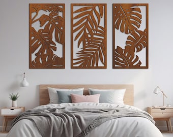 May include: Three wooden wall decor panels with a tropical leaf design. The panels are in a beech wood color and are arranged in a row on a white wall above a bed.