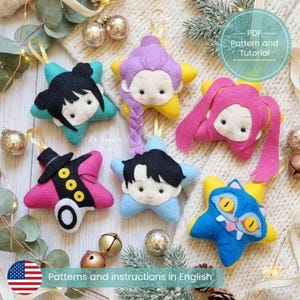 May include: Six star-shaped felt ornaments featuring various character designs, including faces with black, purple, and pink hair, a character with a top hat, and a blue cat-like creature with yellow eyes. Each ornament includes a hanging loop.