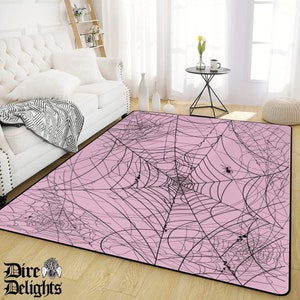 May include: A pink area rug with a black spiderweb design. The rug features multiple black spiders in the web.