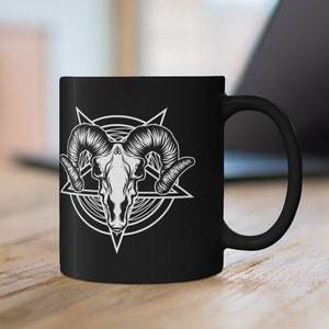 May include: Black ceramic coffee mug with a white graphic of a ram skull inside a pentagram.