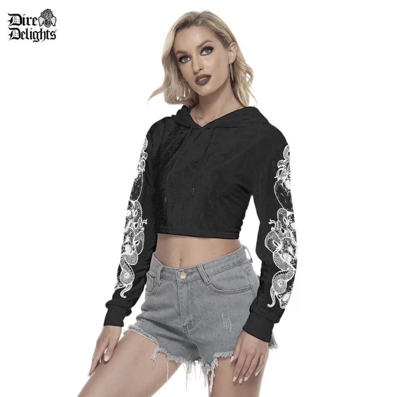 May include: Black cropped hoodie with long sleeves featuring a white snake design. The hoodie has a drawstring hood.