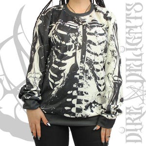 May include: Black and white skeleton-print sweatshirt. The long-sleeved top features a rib cage design on the front and back. The cuffs and hem are dark gray. The sweatshirt is a casual garment.