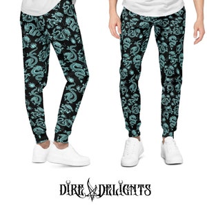 May include: Black sweatpants featuring a teal dragon design. The trousers have a drawstring waist and cuffed ankles. The image also displays the brand name "Dire Delights" in a gothic font.