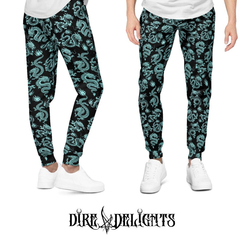 May include: Black sweatpants featuring a teal dragon design. The trousers have a drawstring waist and cuffed ankles. The image also displays the brand name "Dire Delights" in a gothic font.