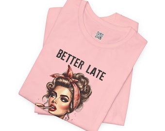 May include: Pink t-shirt with a graphic of a woman with red lipstick and a red bandana, and the text "Better Late".
