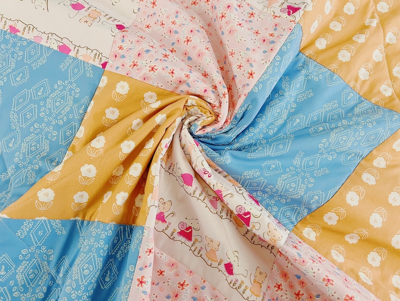 May include: A patchwork quilt with a variety of floral patterns in shades of blue, yellow, pink, and white. The quilt is made of different fabrics and textures, creating a unique and interesting design.