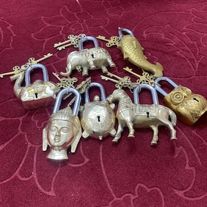 May include: A collection of eight brass padlocks with animal and religious figures. The padlocks are in various shapes, including a camel, elephant, turtle, horse, owl, and Buddha. Each padlock has a keyhole and comes with a matching key.