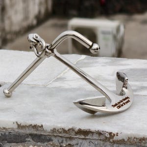 May include: A polished silver anchor with a curved shank and two flukes. The anchor has a ring at the top and a crossbar. The text "Thank you for blending CBS for 20 years!" is engraved on the fluke.