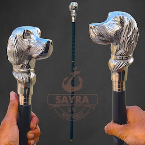 May include: A silver dog head walking cane with a black handle. The dog head is intricately detailed, and the cane features a twisted dark green shaft. A decorative walking stick.
