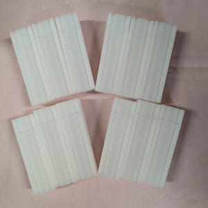May include: Five stacks of white rectangular soap bars. Each stack is made up of five bars.