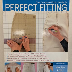 May include: A book titled "The Complete Photo Guide to Perfect Fitting" with a blue banner. The cover features garment patterns, hands measuring fabric, and the text "More than 650 Large Format Color Photos."