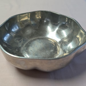 May include: A silver, scalloped serving bowl with a smooth, reflective surface.