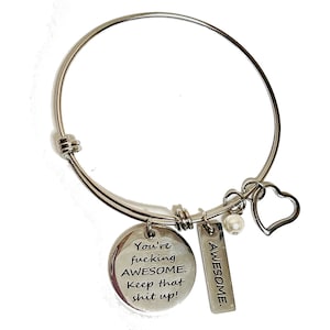 May include: Silver expandable bracelet with a charm that reads "You're fucking AWESOME. Keep that shit up!" and a charm that reads "AWESOME". The bracelet also has a small heart charm and a pearl.