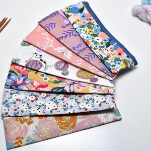 Puede incluir: Un conjunto de ocho bolsas de tela con varios diseños florales y estampados. Las bolsas están dispuestas en forma de abanico, con la bolsa superior con un borde azul.